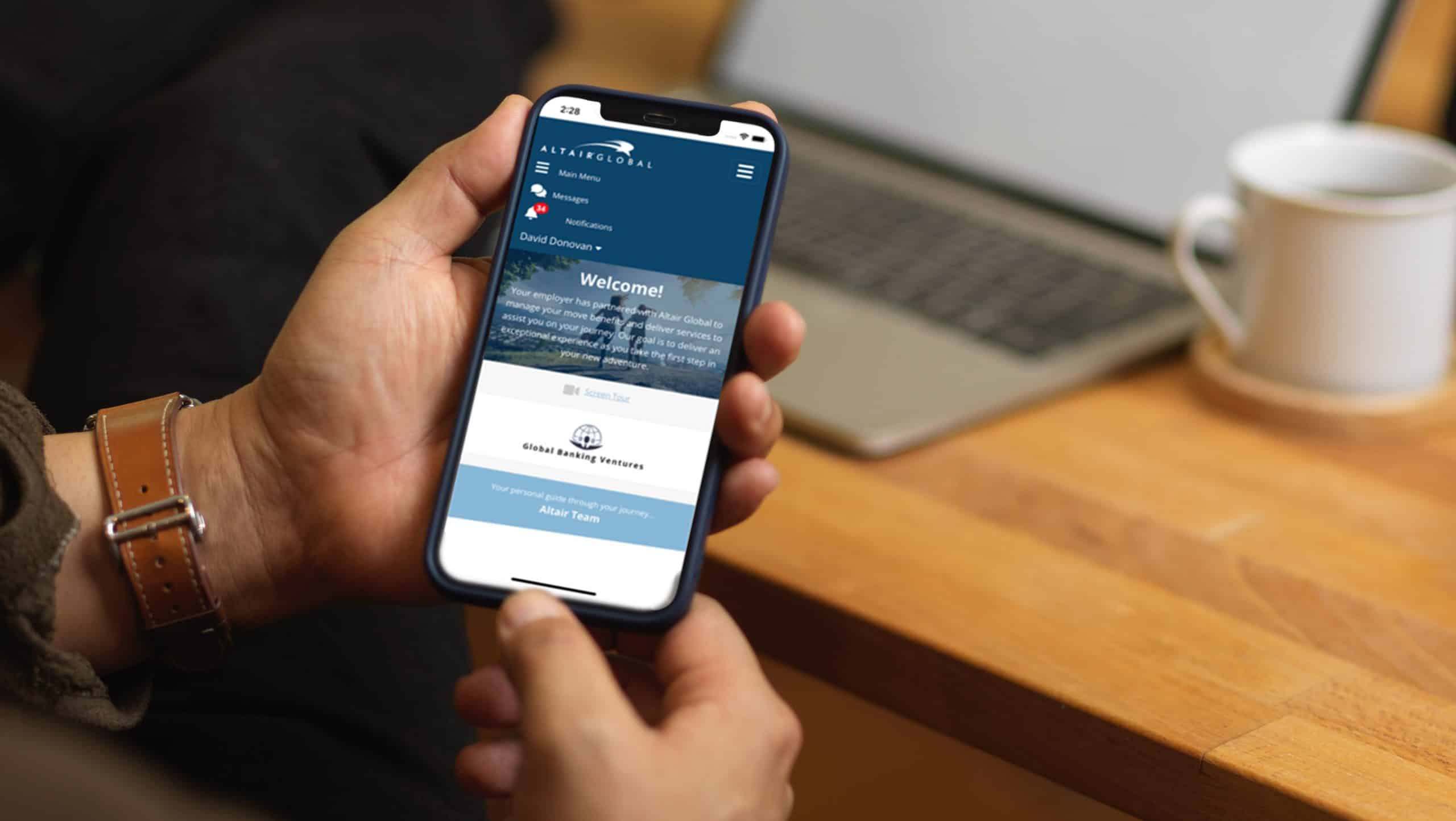 Male hands using smartphone while sitting at workplace with laptop and supplies Altair Anywhere HOme Screen mockup copy e1639003817378