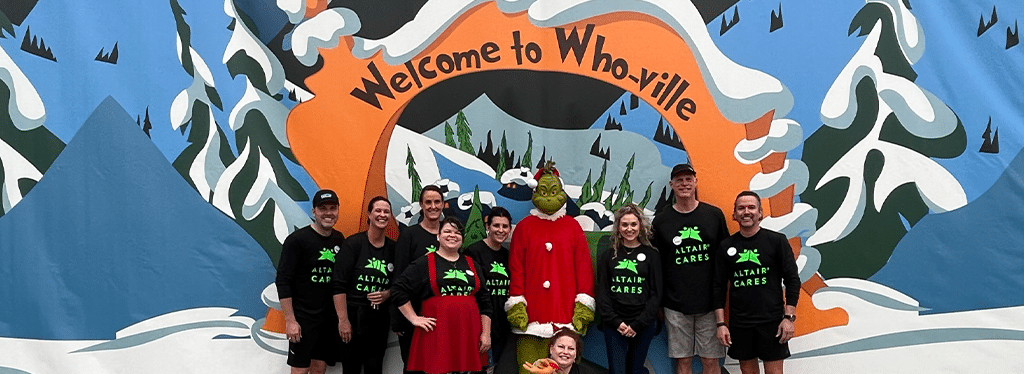 Group of Altair Global Employees in front of Welcome to Who-ville sign, where the relocation company collected 45,000 Meals in Annual Holiday Food Drive Benefitting Move For Hunger and North Texas Food Bank